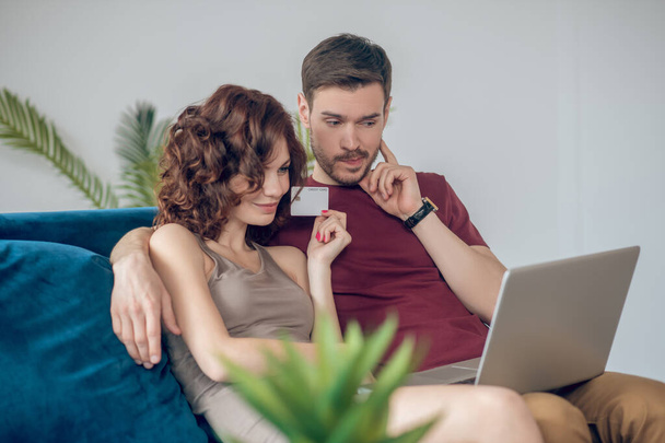 A man and a woman sitting on the sofa with a laptop - 写真・画像