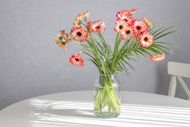 Bouquet of pink gerberas, flowers in a vase on a table in a home interior. Decorations, home decoration, cosiness creation. Floristics, gifts. Copy space - Photo, Image