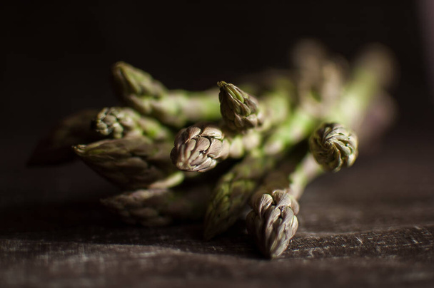 Bunch of fresh green asparagus on dark wooden table, healthy eating, seasonal products - Photo, Image
