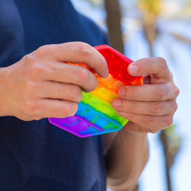 Man with rainbow anti stress pop it toy, outdoors - Photo, Image