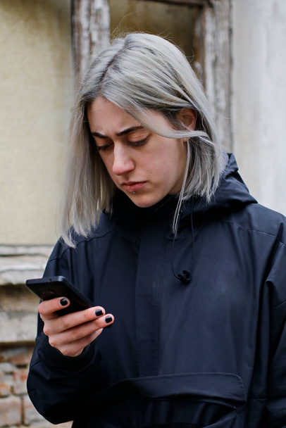 портрет девушки с серебристыми волосами с помощью смартфона на улице - Фото, изображение