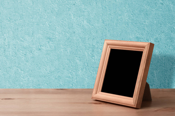 wooden photo frame on table, blue wall - Fotó, kép