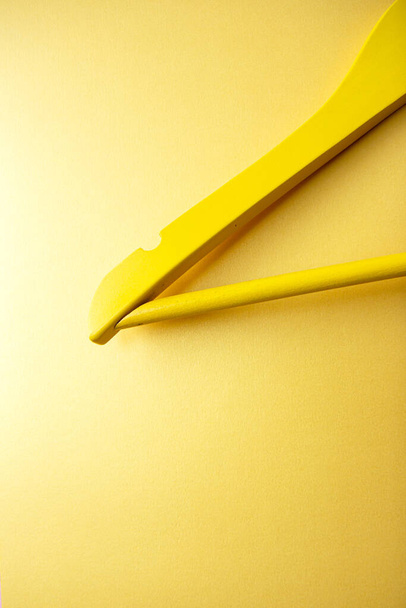 Un cintre en bois jaune sur fond jaune vif. Pose plate créative avec espace de copie. Concept commercial - Photo, image