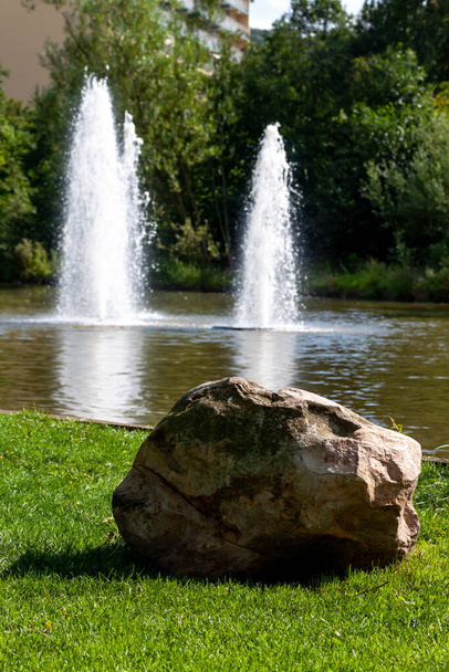 A vertical shot of a big stone in front of a fountain in the park - Photo, image