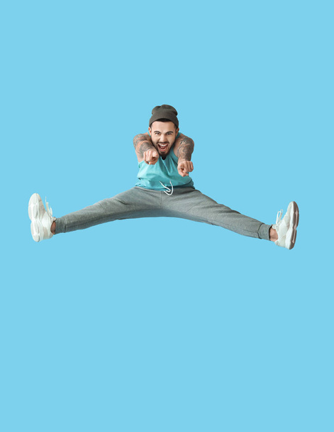 Renk arkaplanındaki izleyiciye bakan zıplayan genç adam - Fotoğraf, Görsel