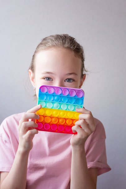Chica adolescente jugando con silicona redonda colorido anti estrés pop it juguete. Empuja Pop Bubble en las manos. De cerca.. - Foto, imagen