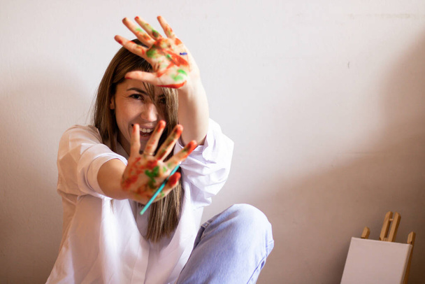 Ein süßes künstlerisches Weibchen zeigt ihre Handflächen in Farbe - Foto, Bild