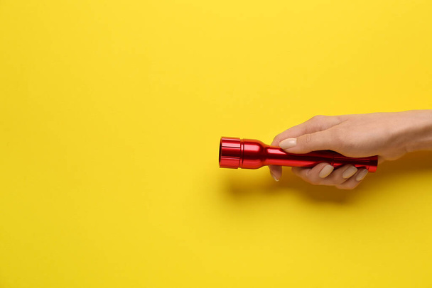 Female hand with modern flashlight on color background - Photo, Image