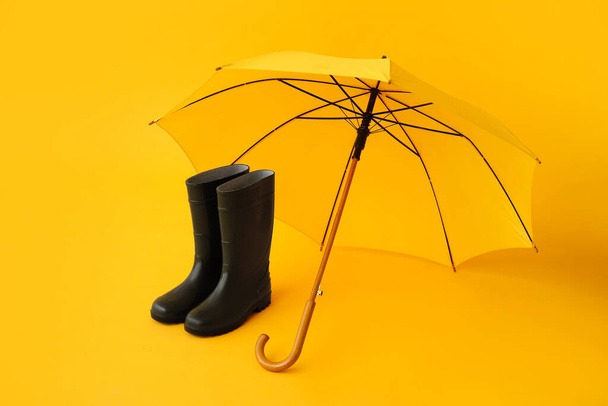 Paraguas elegante y botas de goma sobre fondo de color - Foto, imagen