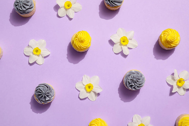 Tasty cupcakes with beautiful narcissus flowers on color background - Foto, imagen