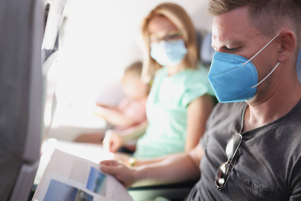 Молода сім'я літає в літаку в захисній медичній масці
 - Фото, зображення