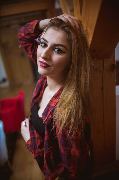 A vertical shot of a Caucasian female with a red checkered shirt at home - Fotó, kép