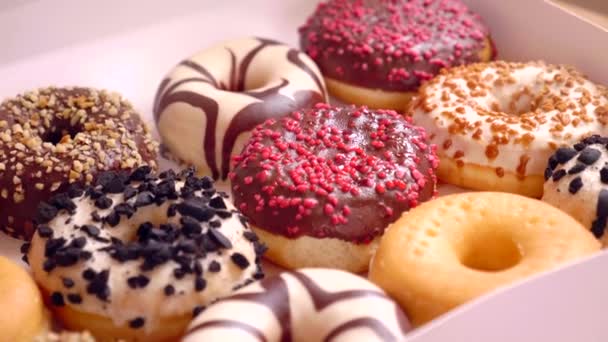 Assortiment van donuts van verschillende smaken in een doos.  - Video