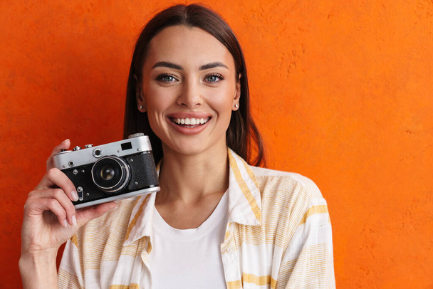 Happy cheerful woman holding photo camera isolated over gray background - 写真・画像