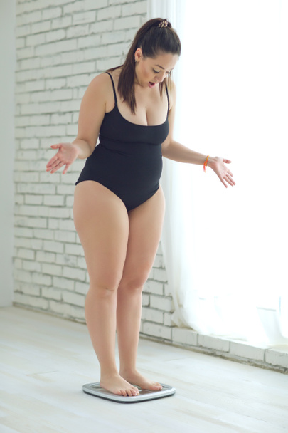 Una mujer gorda se pesa y no puede usar buena ropa.. - Foto, Imagen
