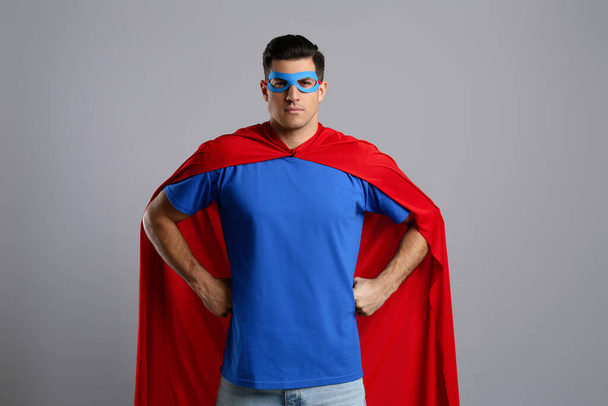 Man wearing superhero cape and mask on grey background - Fotoğraf, Görsel