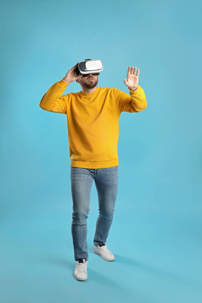 Man using virtual reality headset on light blue background - Foto, immagini