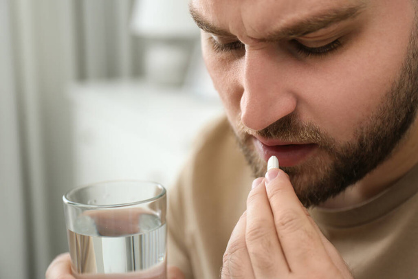 Man taking pill against migraine at home, closeup - Foto, immagini