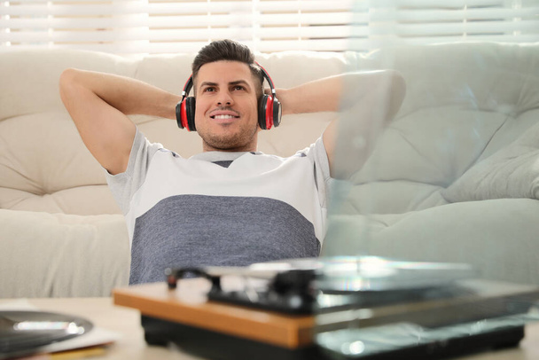Happy man listening to music with turntable at home - Фото, зображення