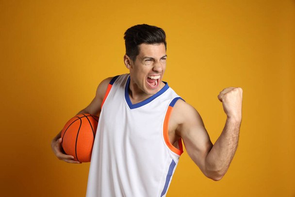 Basketball player with ball on yellow background - Foto, Imagem