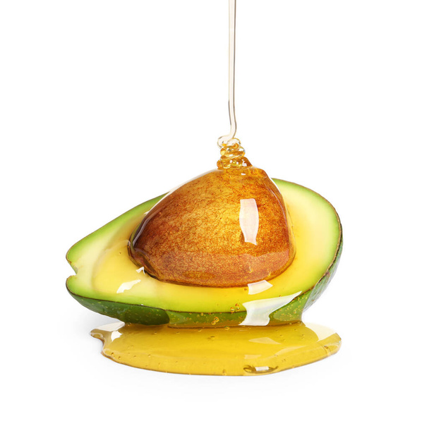 Pouring essential oil onto cut avocado on white background - Foto, Imagem