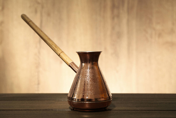 Beautiful copper turkish coffee pot on wooden table - Фото, изображение