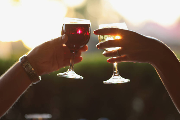 Muž a žena cinkání sklenice s vínem na pozadí západu slunce - Fotografie, Obrázek