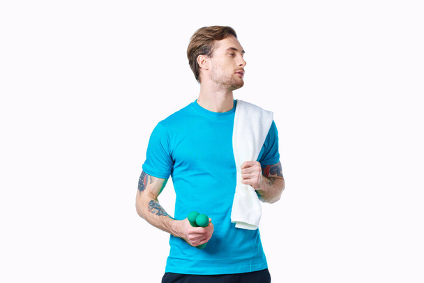 ハンドタオルのダンベルを持つ男肩のトレーニングフィットネスライトの背景 - 写真・画像