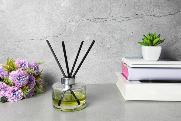 De luxe aromatische riet diffuser helder kristalglas display op de grijze werktafel tijdens het werk van thuis tot creat ontspannen omgeving - Foto, afbeelding