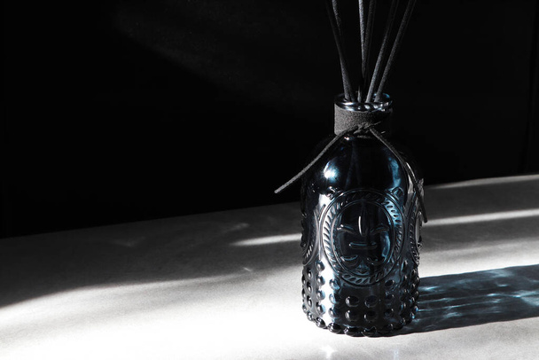 exibição de garrafa de vidro difusor de palheta de aroma de design de luxo na mesa cinza no quarto perto da janela durante a tarde de luz solar - Foto, Imagem