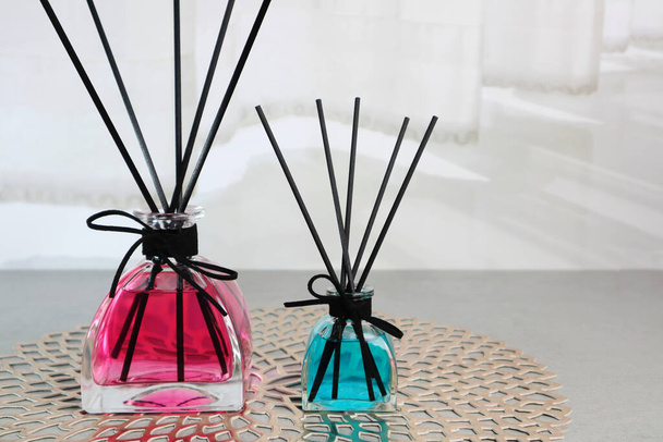 luxury aromatic scented reed diffuser glass bottle display on the grey table in the white bedroom near the white curtain - Photo, Image