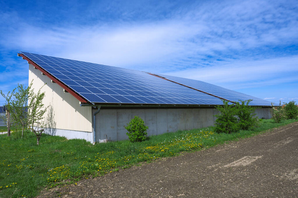 Zöld energia napkollektorokkal egy mezőgazdasági épület tetején - Fotó, kép