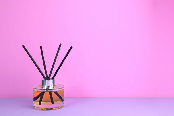 πολυτελή αρώματα άρωμα καλάμι διάχυση γυάλινα μπουκάλια διακοσμούν την οθόνη στο μωβ τραπέζι με φόντο ροζ τοίχο τσιμέντου στο σαλόνι την ημέρα του Αγίου Βαλεντίνου - Φωτογραφία, εικόνα