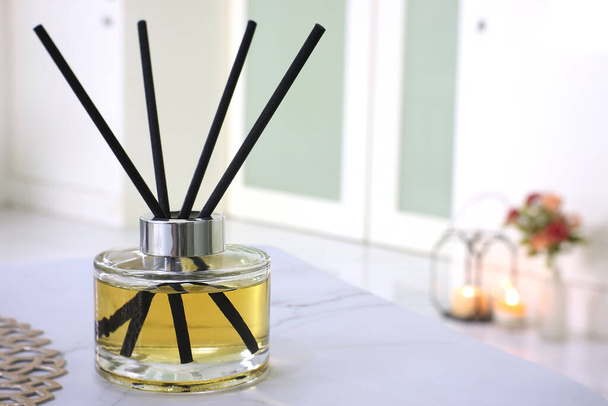  luxury aromatic scent of reed diffuser glass bottle is used as room freshener on the marble table with scented candle in the bedroom with background of the light from the window in the morning - Valokuva, kuva