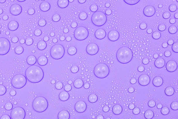 Water drops on purple background texture. Backdrop glass covered with drops of water.  violet bubbles in water - Fotó, kép