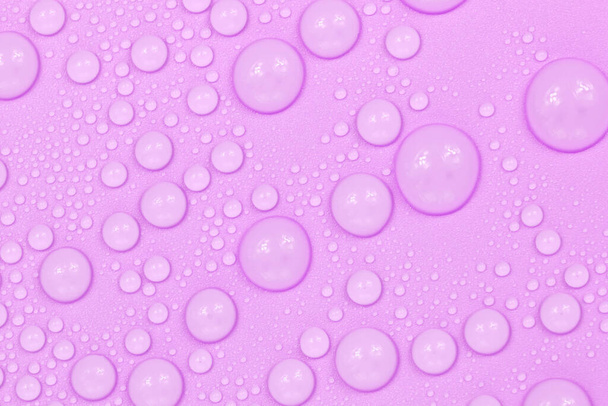 水は紫色の背景の質感に落ちます。背景ガラスは水滴で覆われています。水の中の紫色の泡 - 写真・画像