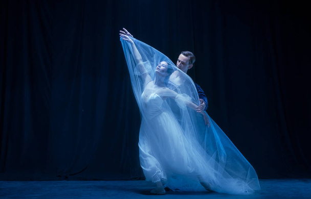 ウェディングドレスと男性の若い女性、暗い背景の上に隔離された芸術パフォーマンスダンスの2人のバレエダンサー. - 写真・画像