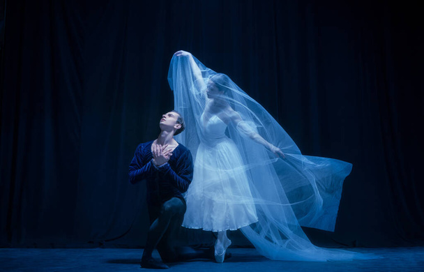 Mujer joven en vestido de novia y hombre, dos bailarines de ballet en performance de arte bailando aislados sobre fondo oscuro. - Foto, imagen