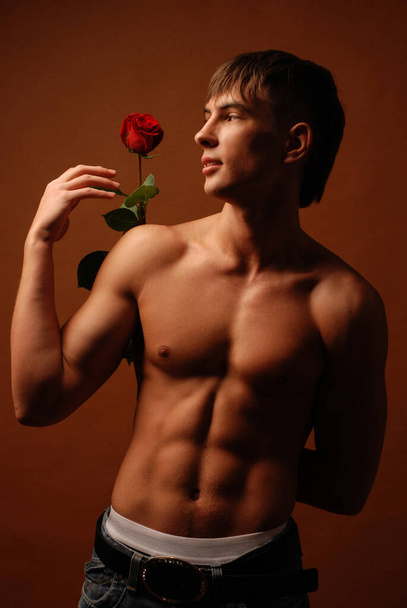 Fitness model posing in studio with a rose - Foto, afbeelding