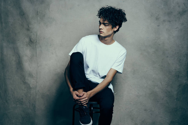 man with curly hair sitting on a chair fashion studio - Photo, image