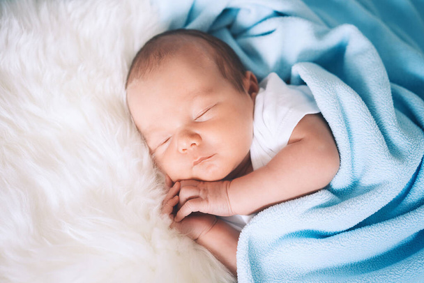 Newborn baby sleep at first days of life. Portrait of new born child boy one week old sleeping peacefully in crib in cloth background. - Фото, изображение