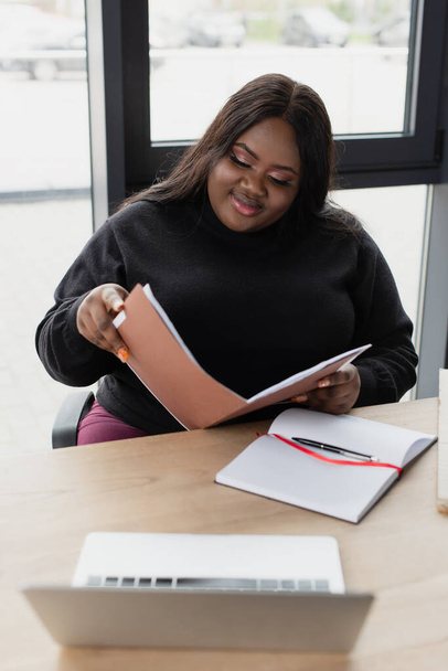 african american plus size woman smiling while looking at folder  - Photo, Image