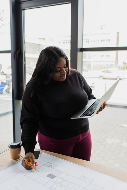 Αφροαμερικανοί συν μέγεθος μηχανικός κρατώντας laptop και σχέδιο σχέδιο  - Φωτογραφία, εικόνα