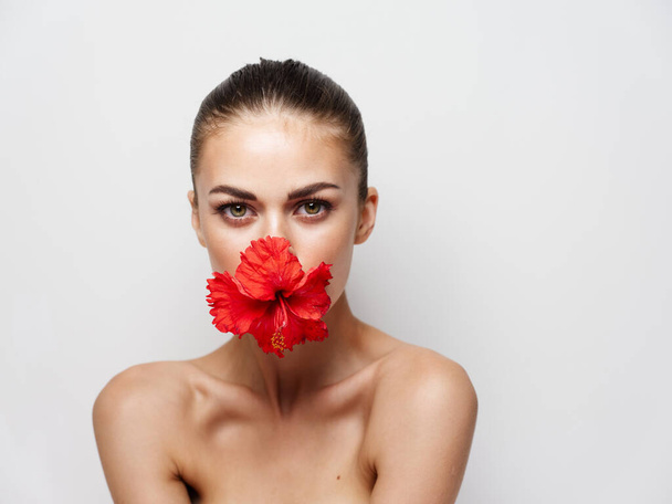 γυναίκα με ένα λουλούδι στο στόμα της γυμνοί ώμοι κοντινό πλάνο στούντιο - Φωτογραφία, εικόνα