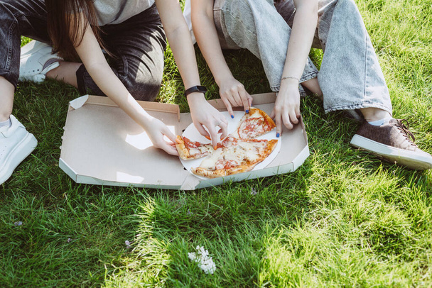 人々はファーストフードを食べる。ピザのスライスを取る友人の手健康食品ではありません。柔らかい選択的フォーカス. - 写真・画像