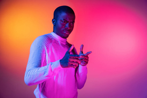 Ein junger glücklicher afrikanischer gutaussehender Mann isoliert über Gradienten rosa gelb neon Hintergrund. - Foto, Bild