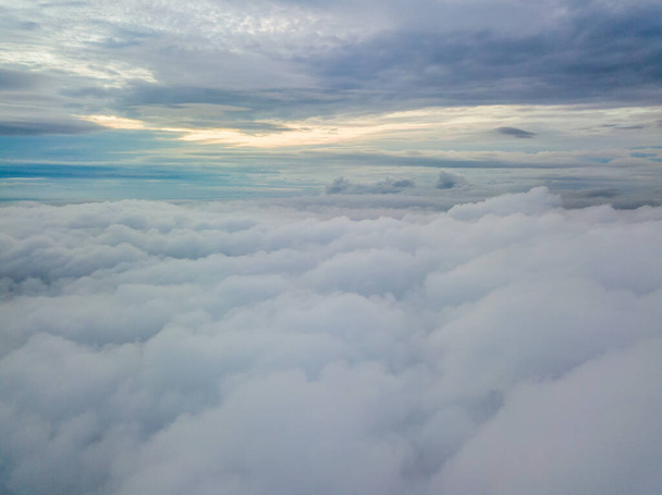 Alto vuelo aéreo por encima de las nubes. Los rayos del sol naciente atraviesan las nubes. - Foto, imagen