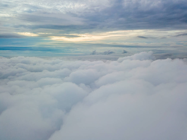 Aerial high flight above the clouds. The rays of the rising sun break through the clouds. - Photo, Image