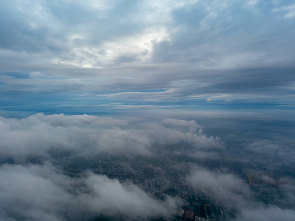 Stad onder de wolken bij zonsopgang. Hoge drone zicht vanuit de lucht. - Foto, afbeelding