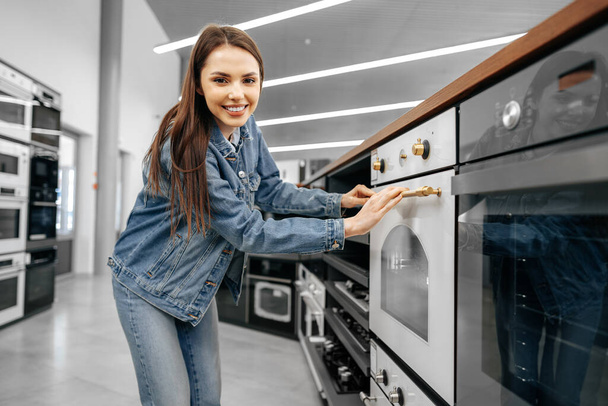 Young woman looking for new electric oven in a shopping mall - Foto, Bild